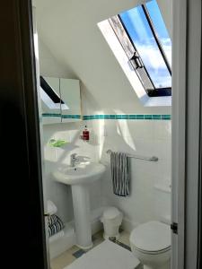a bathroom with a sink and a toilet and a skylight at The Old Post Office Boutique Guesthouse in Hythe