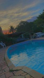 une grande piscine bleue avec un coucher de soleil en arrière-plan dans l'établissement Pisco Chalés, à Ubatuba