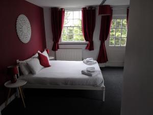 a bedroom with a bed with red walls and windows at The Red Lion in Hythe