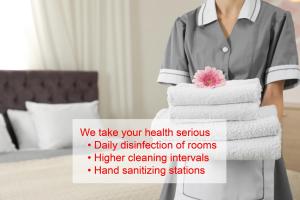 a woman holding a stack of towels in a hotel room at Arosa Kulm Hotel & Alpin Spa in Arosa