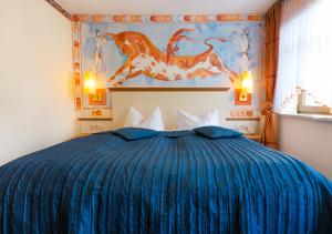 a bedroom with a blue bed with a painting on the wall at Hotel & Ferienwohnungen Bohlenblick in Saalfeld