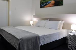 a bedroom with a large white bed with two lamps at Balonne River Motor Inn in Saint George