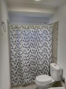a bathroom with a toilet and a black and white shower curtain at Aluminé in Colón