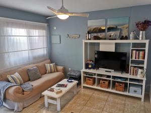 een woonkamer met een bank en een tv bij Salitre in La Caleta