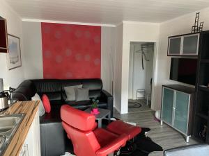 ein Wohnzimmer mit einem schwarzen Ledersofa und roten Stühlen in der Unterkunft Haus Encore in Büsum