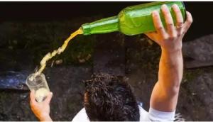 una persona che tiene in aria una bottiglia verde di ALBOR II a Gijón
