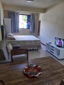 1 dormitorio con 1 cama, TV y sofá en Beira Mar Jurere kit, en Florianópolis