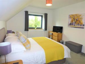 - une chambre avec un lit jaune et blanc et une fenêtre dans l'établissement Gerycastell Luxury Holiday Apartment with Stunning Views & EV Station Point, à Carmarthen