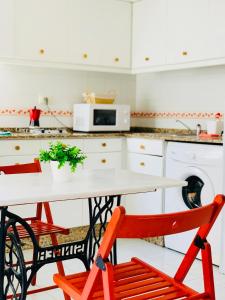 a kitchen with a white table and two red chairs at Estudio 2 en centro Pontevedra in Pontevedra