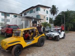 a group of people are riding in a toy car at Lindo apartamento, pertinho do mar e com vista in Maragogi