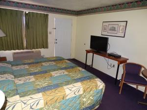 a hotel room with a bed and a desk with a television at Downtown Inn in Albuquerque