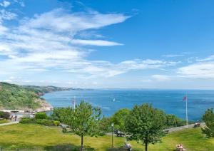 a view of the ocean from a hill with trees at The Downs, Babbacombe in Torquay