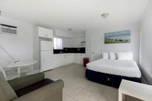 a white bedroom with a bed and a kitchen at Hollywood Broadwalk Oceanside Hotel in Hollywood
