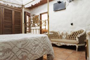 a bedroom with a bed and a couch and a tv at Na-anché Hotel in Oaxaca City