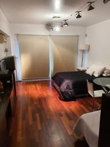 um quarto com uma cama e piso em madeira em Juncal Apartamento em Buenos Aires