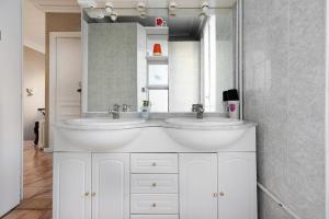 La salle de bains est pourvue de 2 lavabos et d'un miroir. dans l'établissement Cameleon Paris Guesthouse, à Pantin