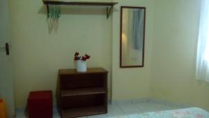 a room with a dresser with a vase of flowers on it at Apto. Cid. Ocian in Praia Grande