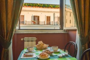 une table avec de la nourriture et une fenêtre avec vue sur un bâtiment dans l'établissement Hotel Giorgina, à Rome