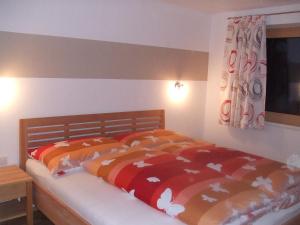 1 dormitorio con 1 cama con edredón naranja y blanco en apArtment kAtrin & gerhArd, en Schwendau