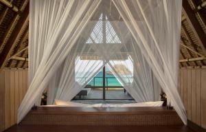 a canopy bed with white curtains in a room at Jeeva Beloam Beach Camp in Tanjung Ringgit