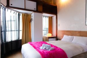 a bedroom with a large bed with a pink blanket at Romance za Kado in Atami