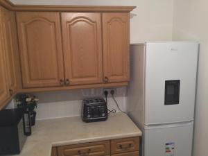 a kitchen with wooden cabinets and a white refrigerator at Quiet Residential Area Within Easy Reach Of Town in Manchester