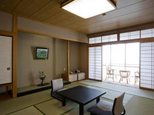 a living room with a table and chairs and a balcony at Mikawa Bay Hills Hotel in Nishio