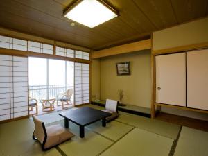 a living room with a table and chairs and windows at Mikawa Bay Hills Hotel in Nishio