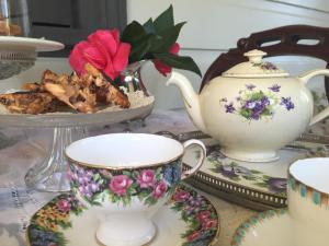 a table with tea cups and a plate of food at Kurrara Historic Guest House in Katoomba