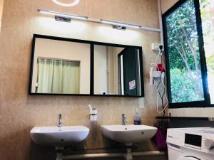 Baño con 2 lavabos y espejo en la pared en CapsulePod@Aljunied en Singapur