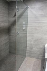 a shower with a glass door in a bathroom at All Nite And Day Palembang Veteran in Palembang