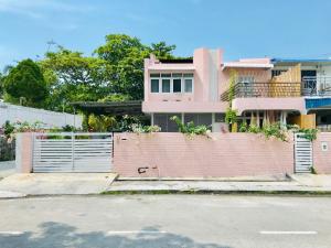 a pink house with a gate and a fence at Smell rose beach garden in Batu Ferringhi