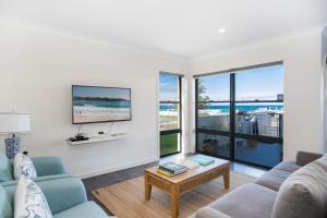 a living room with a couch and a tv at Beachfront One, Mollymook in Mollymook