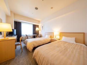 a hotel room with two beds and a television at President Hotel Mito in Mito