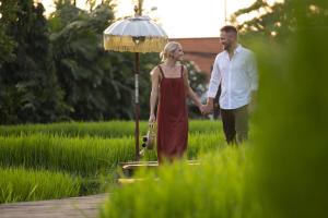 a man and a woman standing in a field with an umbrella at Alaya Resort Ubud - CHSE Certified in Ubud