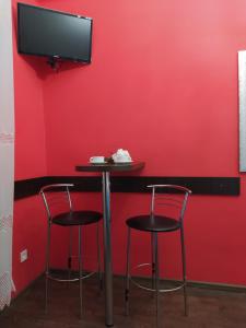 een bar met twee krukken en een tv aan een rode muur bij Cozy studio for couple near Polytechnic University in Lviv