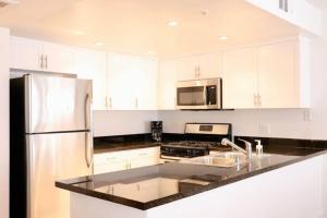 a kitchen with white cabinets and a stainless steel refrigerator at HEART OF WEST HOLLYWOOD MODERN SUITE 2 BEDROOM 2 BATH in Los Angeles