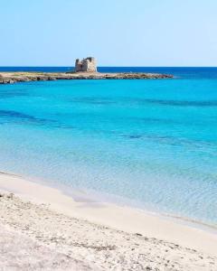 a beach with blue water and a castle in the background at Il Galeone B&B in Pulsano