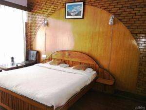 a bedroom with a large bed with a wooden headboard at Parwati in Nainital