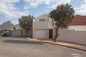 a white house with a garage on the side of a street at 20 belladonna avenue Vredehoek Cape town in Vredehoek
