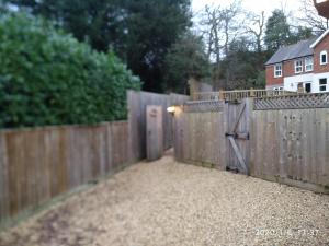 a wooden fence with a door in a yard at Glen Lodges in New Milton