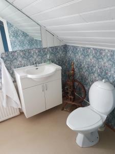 a bathroom with a white sink and a toilet at Guesthouse Gamli Bær in Húsafell