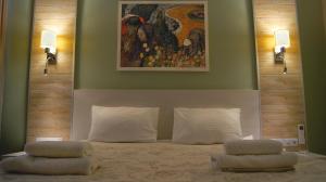 a bedroom with a bed with two pillows and a painting at Hotel Complex Kupecheskiy Dvor in Rostov on Don