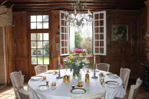 a dining room with a white table with flowers on it at Manoir de la Foulquetiere in Luçay-le-Mâle