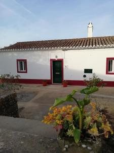 um edifício branco com uma porta verde e algumas flores em Monte da Cruz 18 em Évora Monte