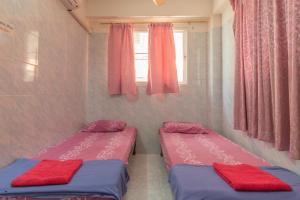 two beds in a small room with pink curtains at New Central Guesthouse in Bangkok