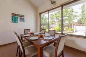 a dining room with a table and chairs and a large window at StayVista's Santoni Farms - Riverside Bliss with Pool, Orchard & Activities in Karjat