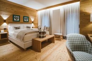サン・ヴィート・ディ・カドーレにあるFIORI Dolomites Experience Hotelのベッドと椅子付きのホテルルーム