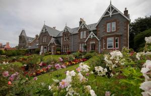 una gran casa de ladrillo con un jardín de flores en Myrtle Bank Guest House, en Fort William