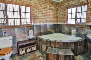 a bathroom with a tub and a toilet and a sink at Adventure Bush House in Marloth Park